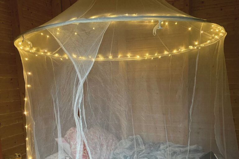 Mosquito net canopy over a bed with fairy lights at a Finnish cottage in summer