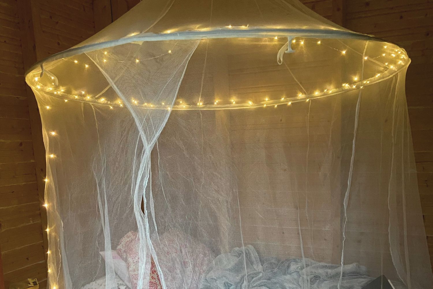 Mosquito net canopy over a bed with fairy lights at a Finnish cottage in summer