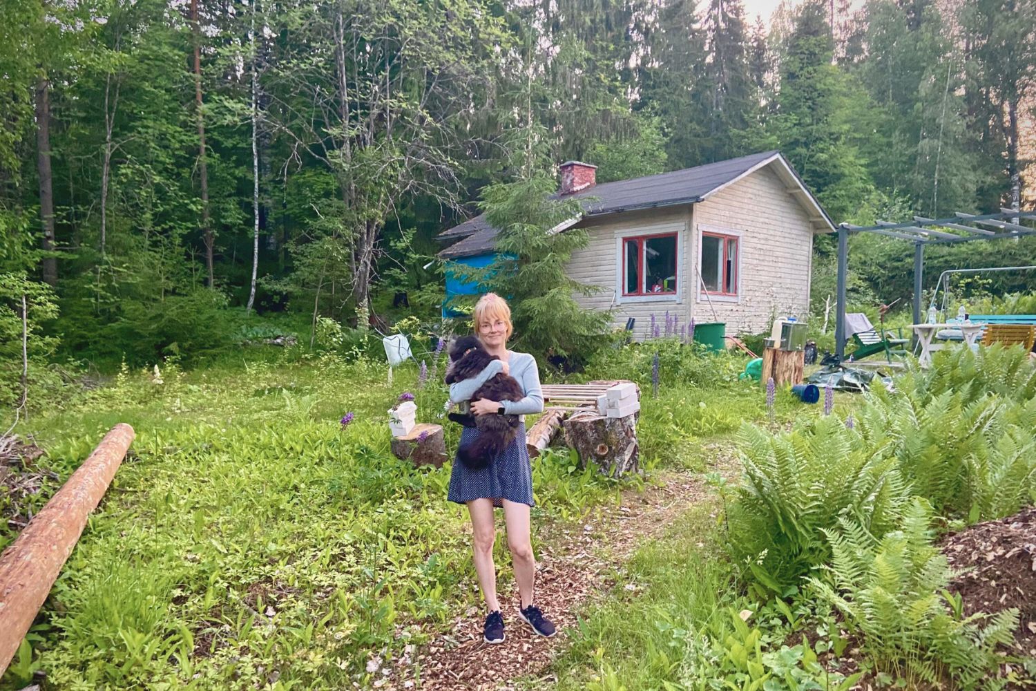 Walking down the path to a Finnish cottage, holding cat Teemu, cottage visible in the background